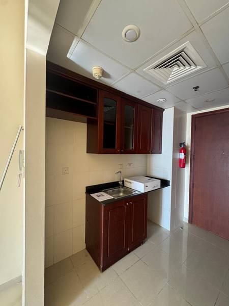 Studio kitchen before — melamine cabinets and chipped floor tiles