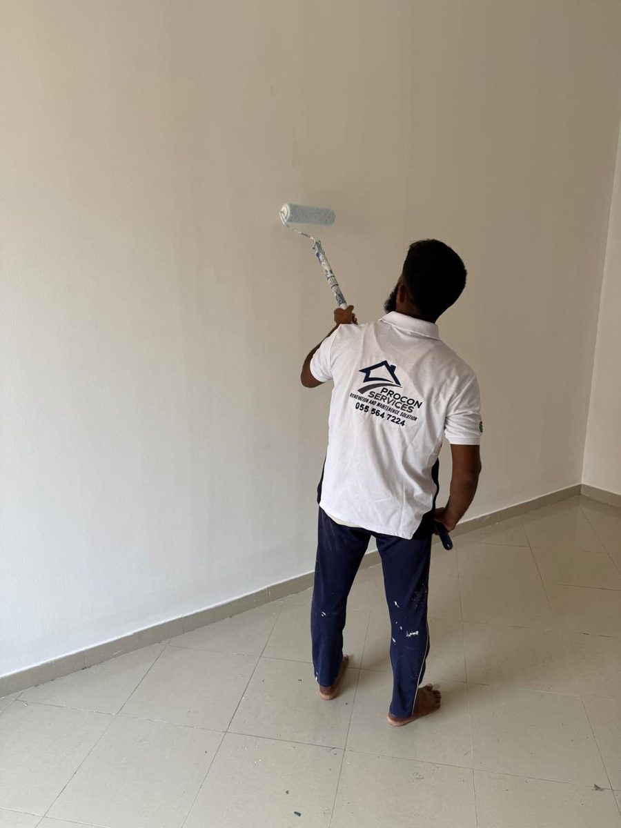 Procon team member painting a wall, branded shirt visible
