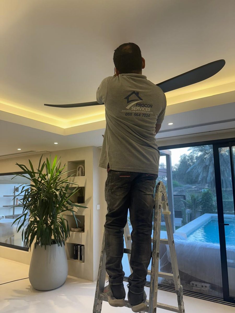 Procon team installing a ceiling fan in a luxury villa with pool view